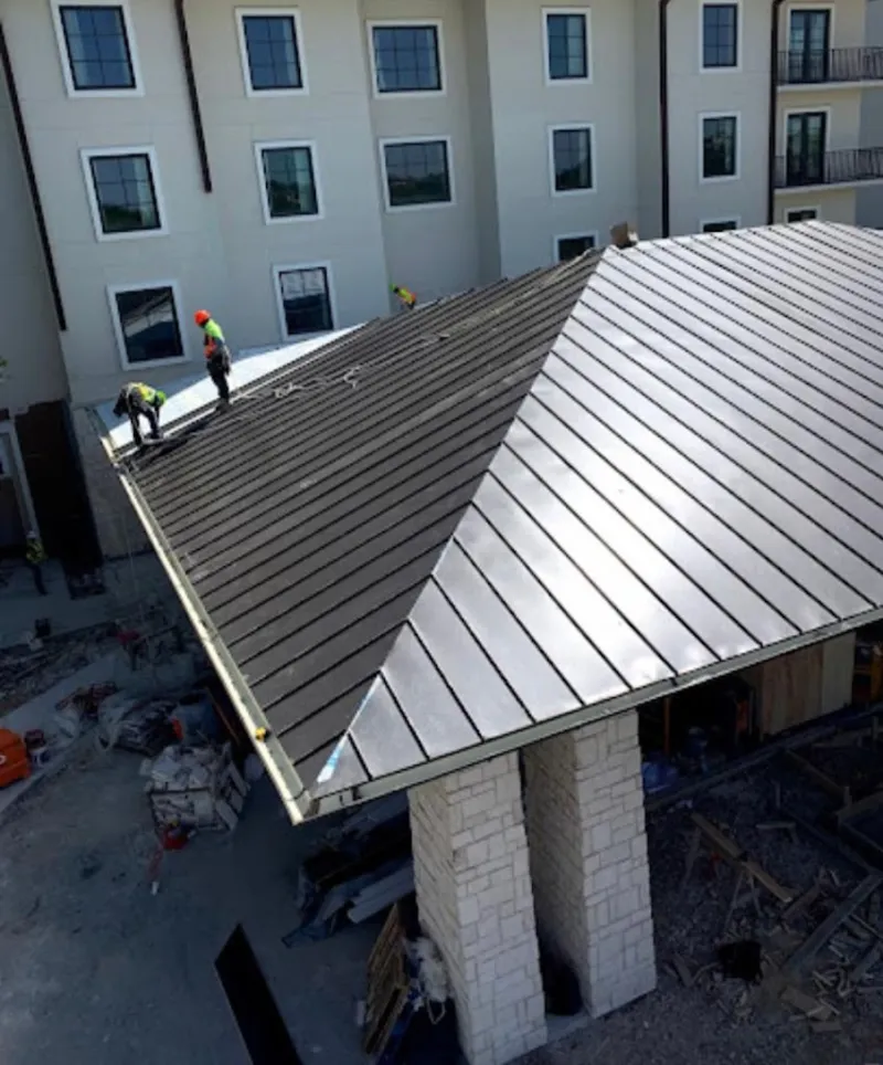 Crew installing standing seam metal roof panels on a commercial project in Yakima